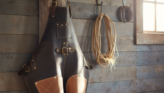 Farrier wearing apron incorrectly while trimming a horse hoof